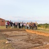 A group of people standing in front of an archaeological excavation site.