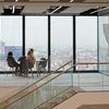 A modern office space featuring a group of people having a discussion with a city view in the background.
