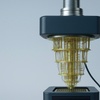 The image depicts a modern device with a distinctive cone-shaped structure made of golden wire.