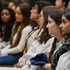 A group of young people is attentively sitting in a seminar or lecture hall.