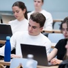 Students using laptops in a university classroom.