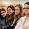 A group of young people sitting in a seminar, smiling and paying attention.