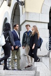 A group of four young adults engage in conversation while standing on steps of a building.
