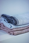 A stack of neatly folded linen fabrics in various muted colors.