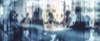 A blurred view of people engaged in a meeting around a table.