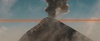 A volcano erupts, releasing smoke and ash into the sky.