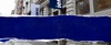 A street view showing a building with a blue and white sign.