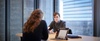 A young man is engaged in a conversation with a woman in a modern office setting.