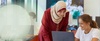 Two women are collaborating on a laptop in a modern workspace.