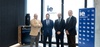 A group of four professionals standing together in a modern office space with a view of the city.