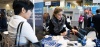 Two women are engaging at a professional event, discussing ideas while examining a laptop.