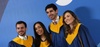 A group of four graduates posing proudly in their academic gowns.