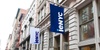 Blue and white flags with the text 'ieNYC' hang outside a building on an urban street.