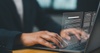 A person analyzing data on a laptop with graphical digital overlays.