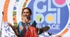 A woman is speaking into a microphone on a stage with a colorful background featuring the text 'Global Village'.