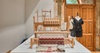 A traditional wooden weaving loom displayed in a room with a mannequin wearing a black garment.