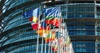 A display of various national flags in front of a modern glass building.