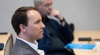 A man seated at a conference table listening attentively.
