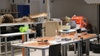 A cluttered workshop filled with various tools and materials on tables.