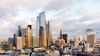 A panoramic view of a modern city skyline with skyscrapers under a cloudy sky.