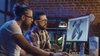 Two men working on a computer design of a drone in a modern office environment.