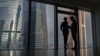 A couple is silhouetted against large urban skyscrapers.