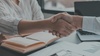 what seems to be a business woman and a business man shaking hands denoting for the viewer they reached an agreement