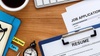 A workspace featuring a job application and resume alongside a cup of coffee and a clock.