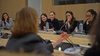 A group of attentive young women listening to a speaker in a conference room.