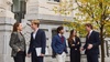A group of young professionals engaged in a discussion outside a building.