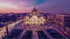 A stunning view of a historic building illuminated at dusk surrounded by vibrant city life.