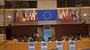 A conference room featuring multiple national flags and the European Union flag.