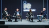 A panel discussion featuring four speakers on stage at an event.