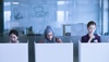 Three women are working quietly in a modern office space with cubicles.