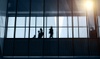 Silhouettes of people walking inside a modern building.