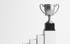 A silver trophy placed on a pedestal representing achievement.