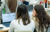 Two people are focused on a laptop screen in a collaborative setting.