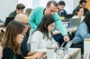 A teacher assists a student during a class in a modern classroom setting.