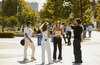 Group of people casually playing with a soccer ball in a sunny urban square.