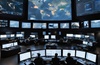 A high-tech control room monitoring Earth from space with multiple screens displaying various data.