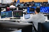 The image shows a group of people working at computers in a modern office environment.