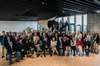A large group of people posing for a photo in a modern office space.