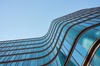 A modern building with flowing glass architecture against a clear sky.