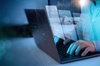 A person is using a laptop with digital graphics of data storage displayed on the screen.