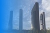 Modern skyscrapers under a blue sky with clouds, showcasing contemporary architecture.