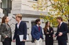 A group of young professionals engaging in conversation outside a modern building during autumn.
