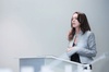 A woman in a blue suit is speaking at a podium in a business or academic setting.