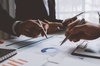 Business professionals analyzing financial charts and documents on a desk during a meeting.