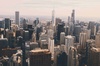 A panoramic view of a city skyline filled with tall buildings under a cloudy sky.