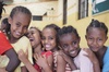 A group of joyful children smiling and embracing each other indoors.